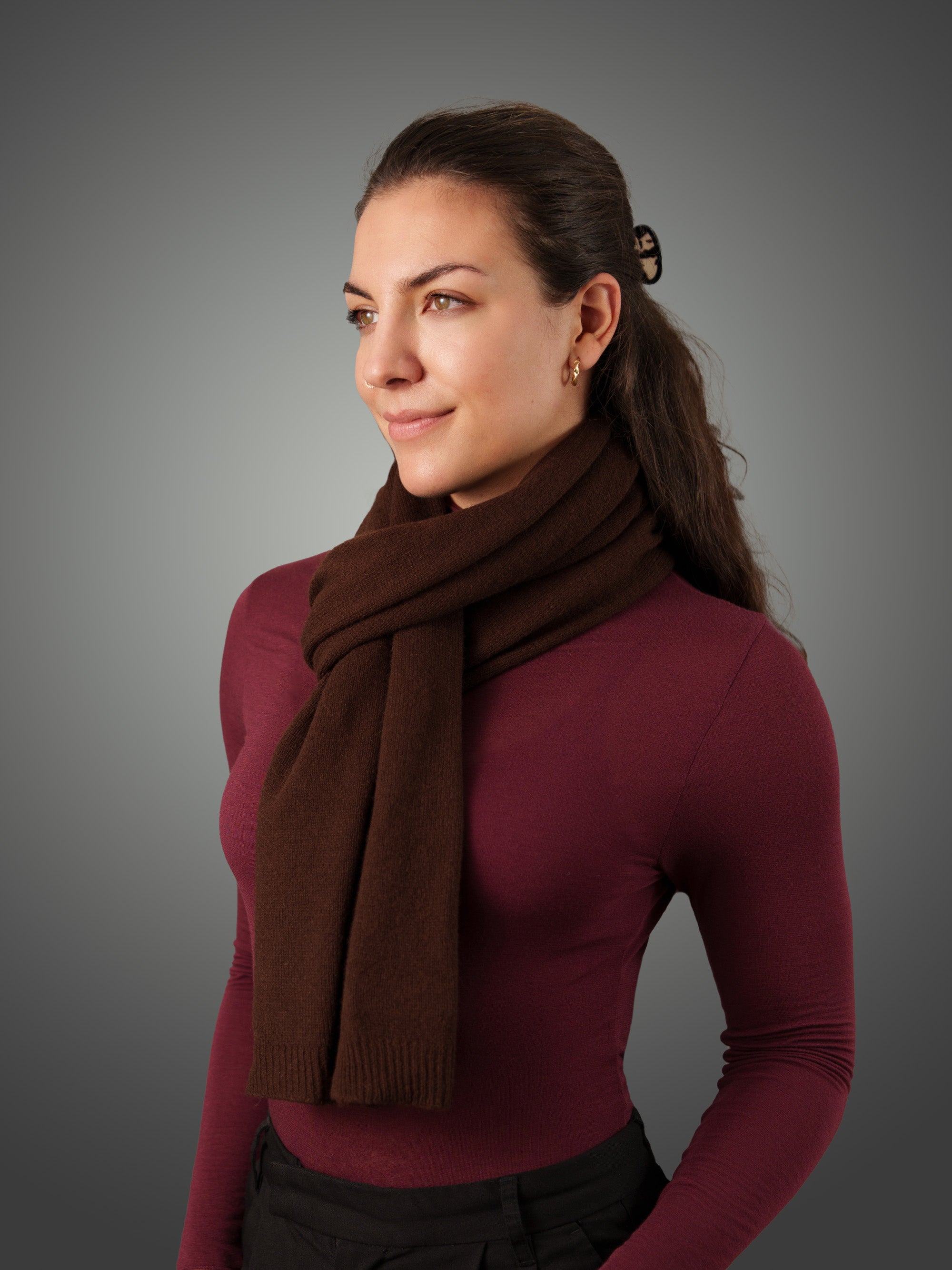 Woman wearing a brown cashmere scarf against a gray background