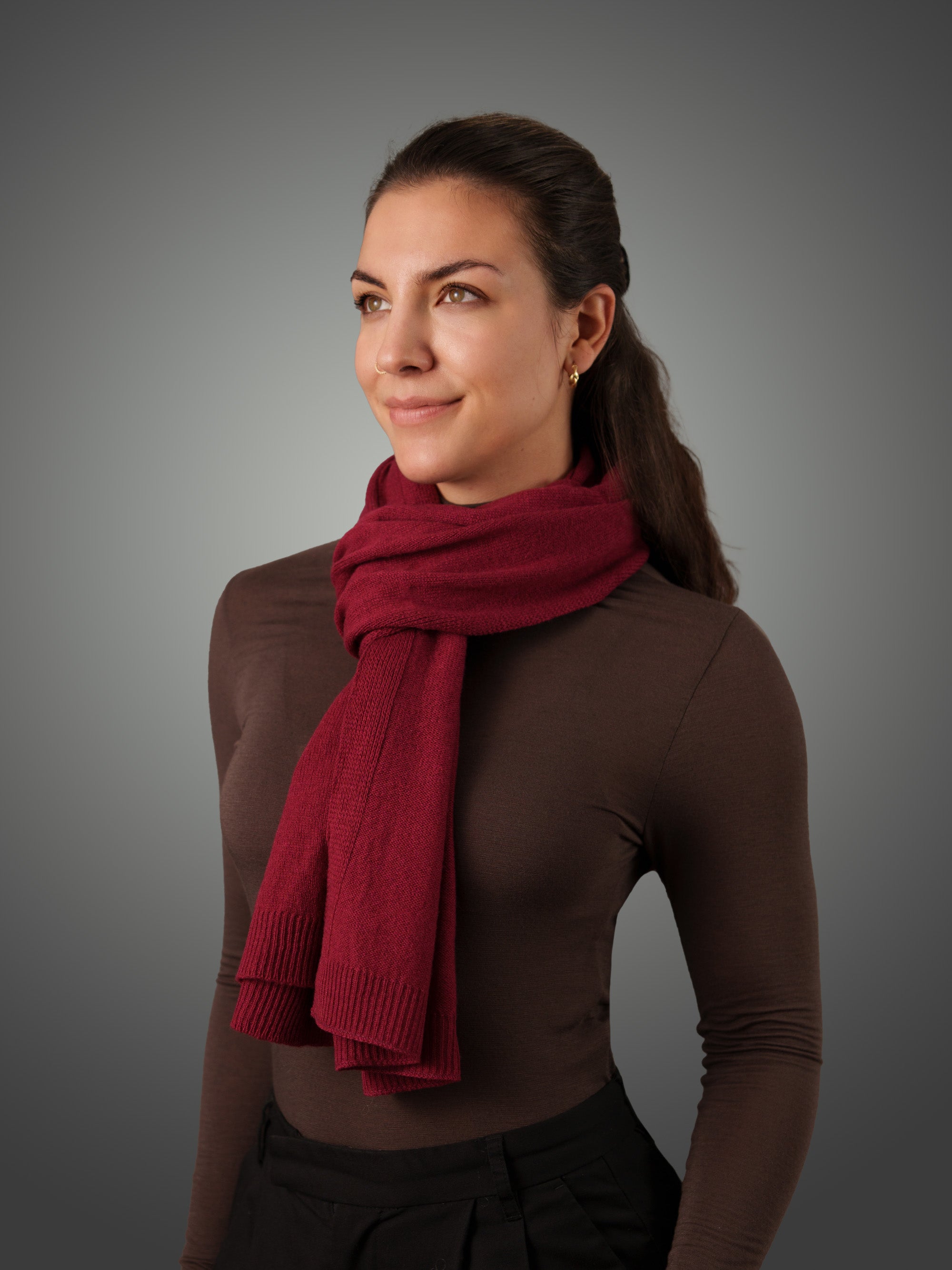 Woman wearing a red cashmere scarf against a gray background