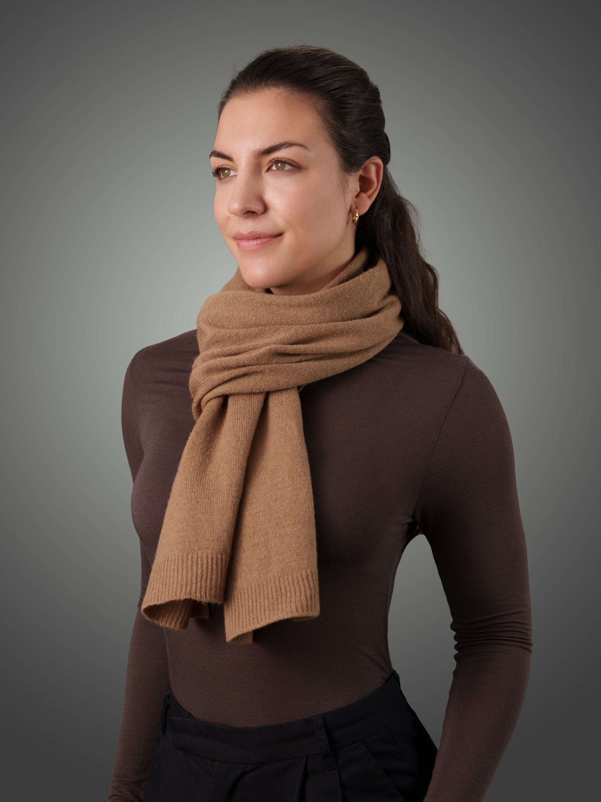 Woman wearing a camel cashmere scarf with gray background